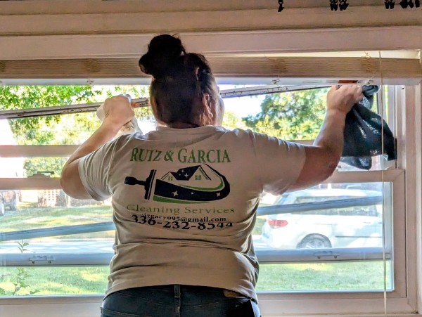 Woman cleaning while wearing a "Ruiz Garcia Cleaning" shirt